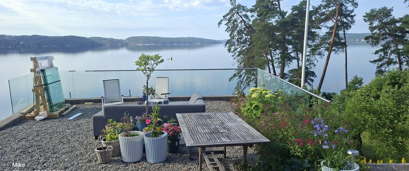 Glassrekkverk med fjordutsikt og hage